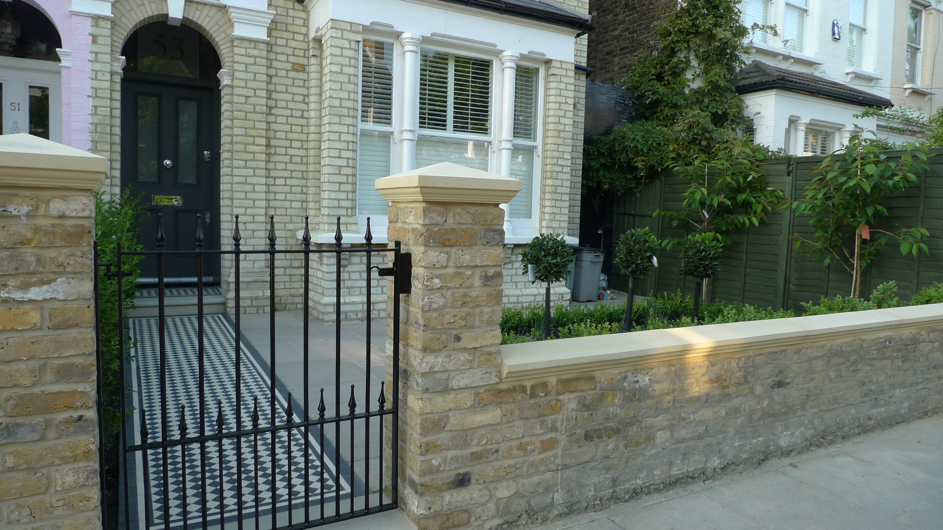 Yellow stock wall stone caps and metal front garden gate front garden London
