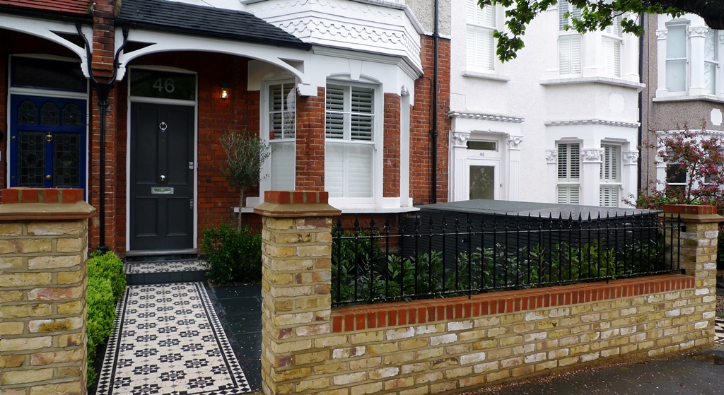 yellow brick london garden wall with metal rail and formal planting hedge