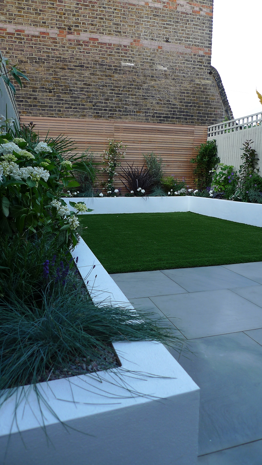 sawn grey sandstone paving raised rendered beds hardwood screen painted stone fence london small garden design (3)